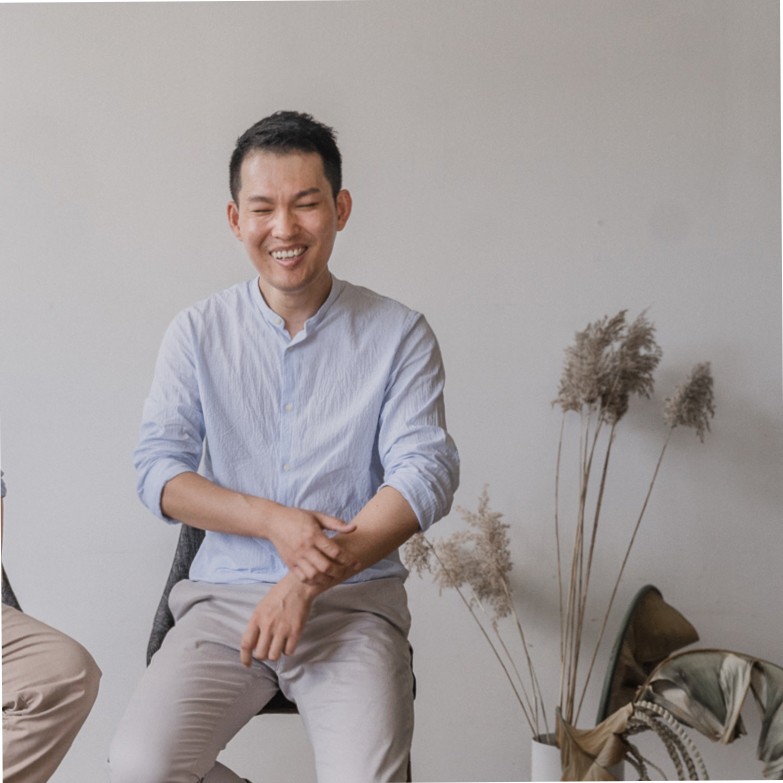 Jeffrey Wang, professional photographer and creative director smiling in front of a white wall next to indoor decor