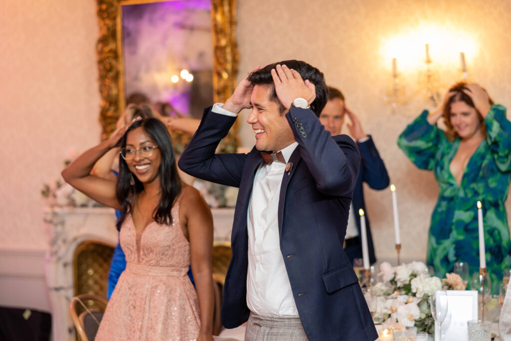 Man in a blue suit and a woman in a pink dress with their hands on their head, smiling, playing a true or false wedding game