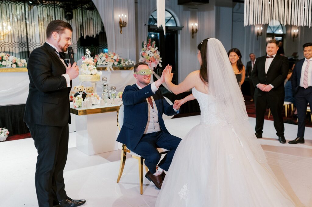 Nathan Cassar Master of Ceremonies at HIGHLINE Venue hosting a unique couple's touching game with the groom wearing funny frog googly eyes