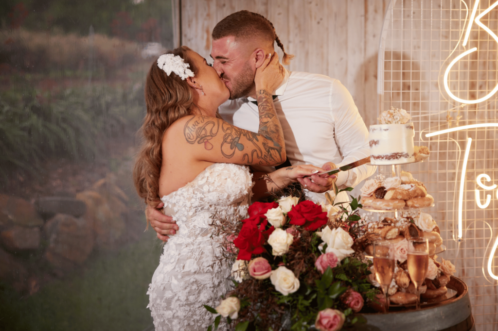 Allison & Ben kissing after their cake cutting at a wedding venue in Sydney, which happens to be Growwild Wildflower Farm hosted by Nathan Cassar Master of Ceremonies