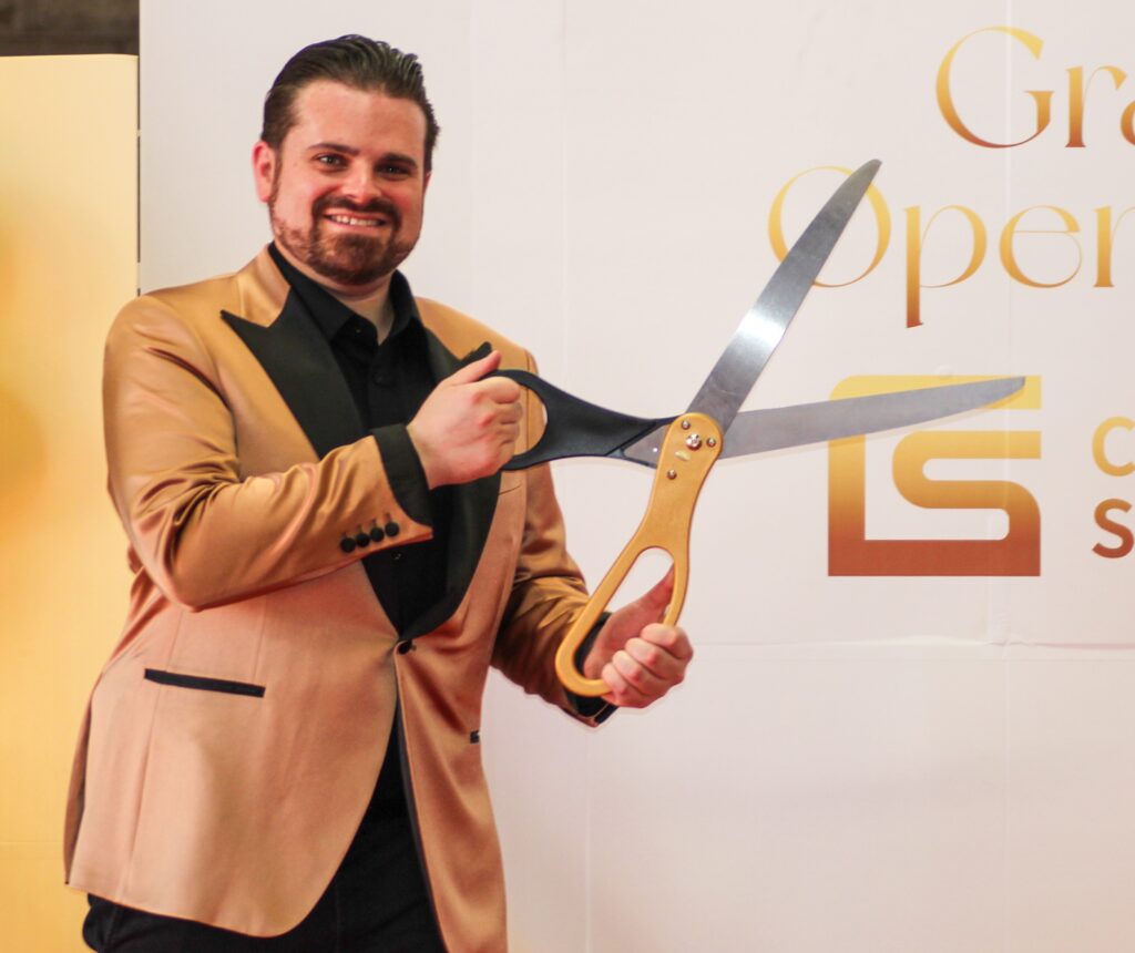 Nathan Cassar, corporate event mc holding oversized ceremonial scissors at opening event