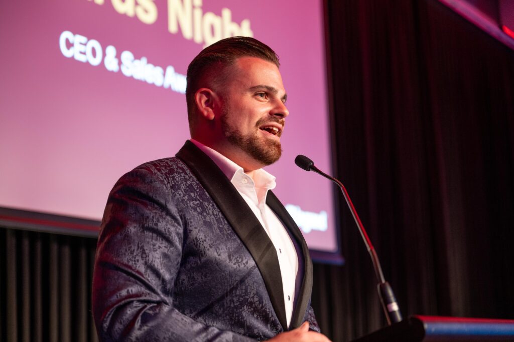 Nathan Cassar, corporate event mc in suit speaking at podium event