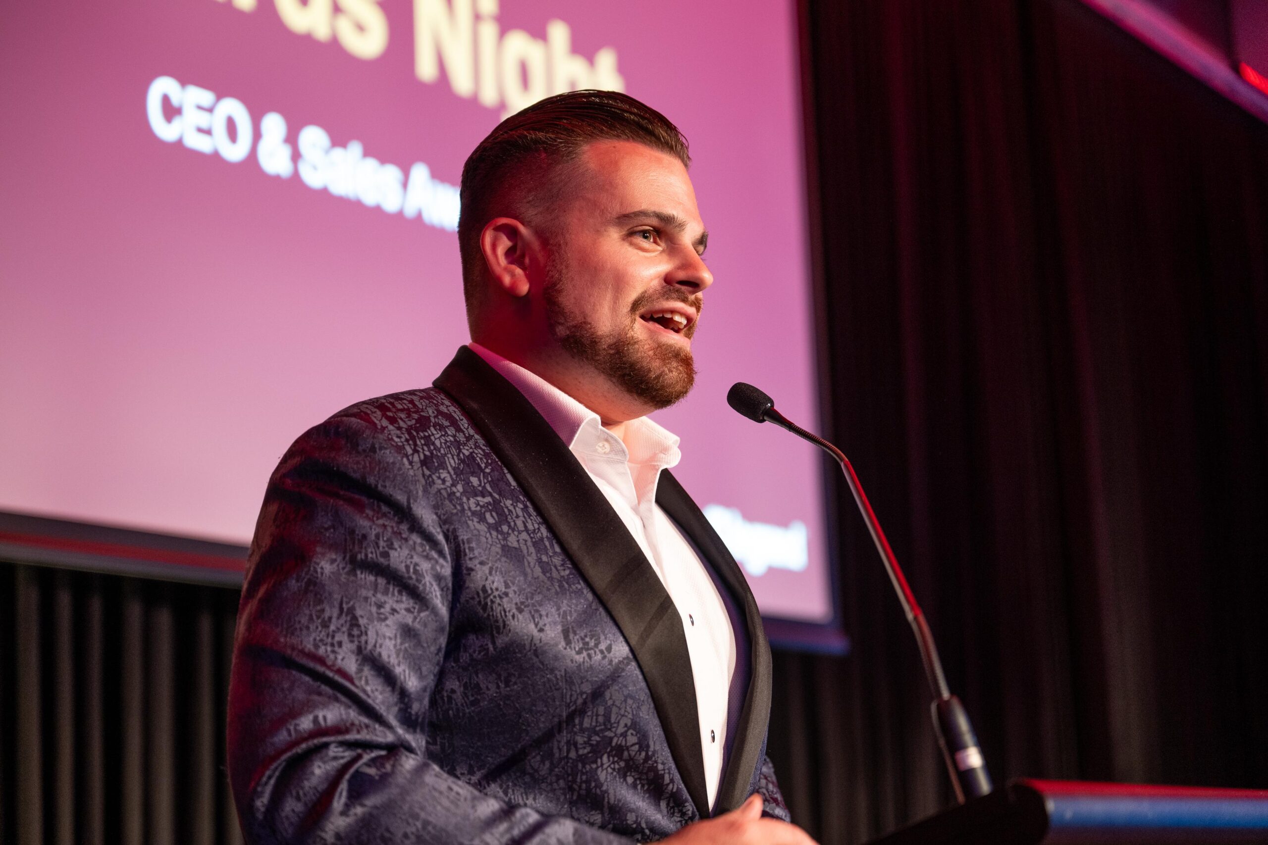 Nathan Cassar, corporate event mc in suit speaking at podium event