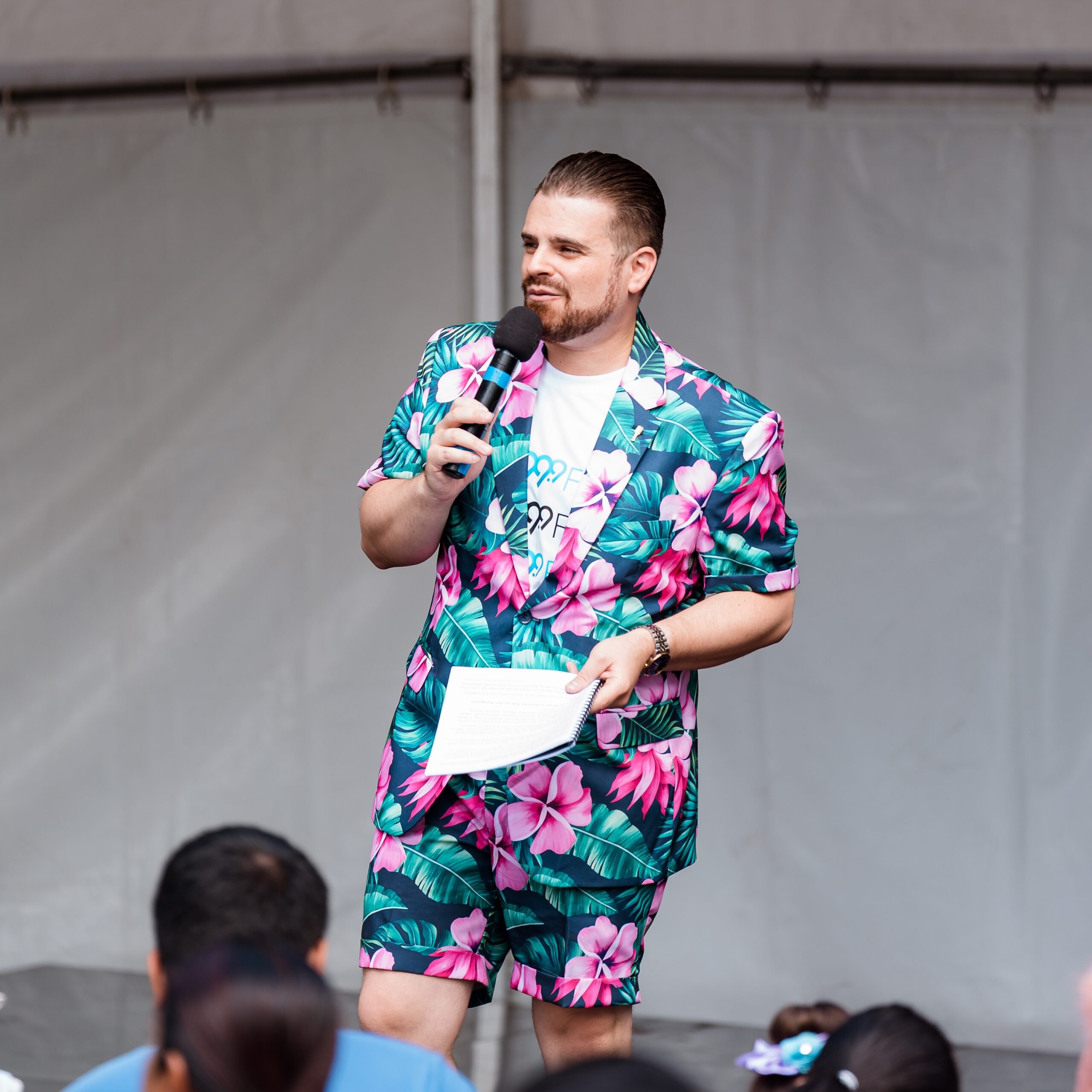 Nathan Cassar, corporate event mc speaking on stage in floral suit