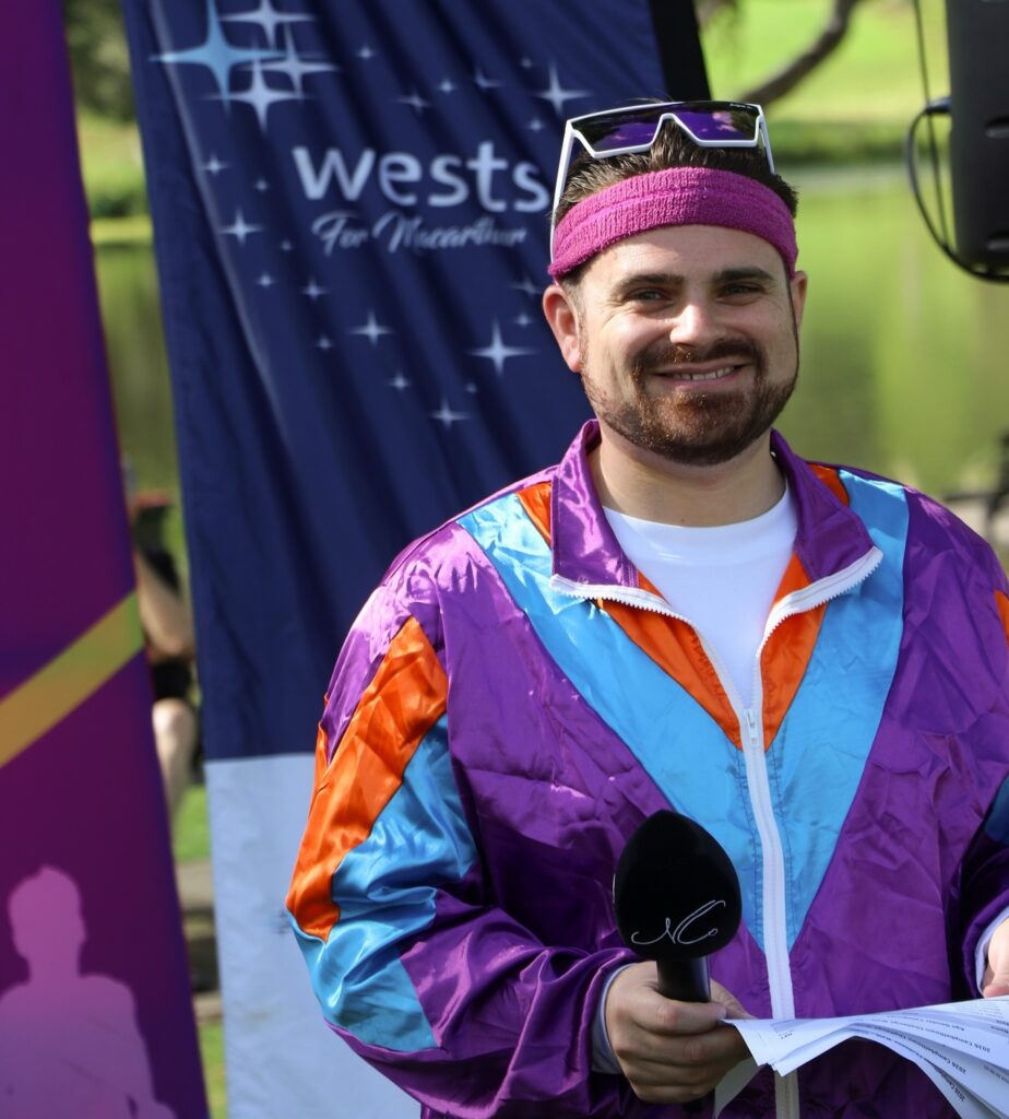 Nathan Cassar, corporate event mc in colourful retro outfit holding microphone outdoors
