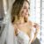 Bride in lace wedding dress looking through window