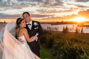 Bride and groom embracing at waterfront sunset