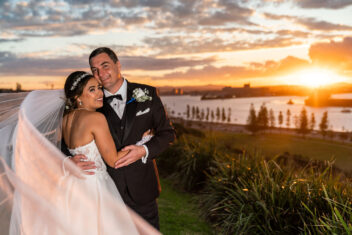 Bride and groom embracing at waterfront sunset