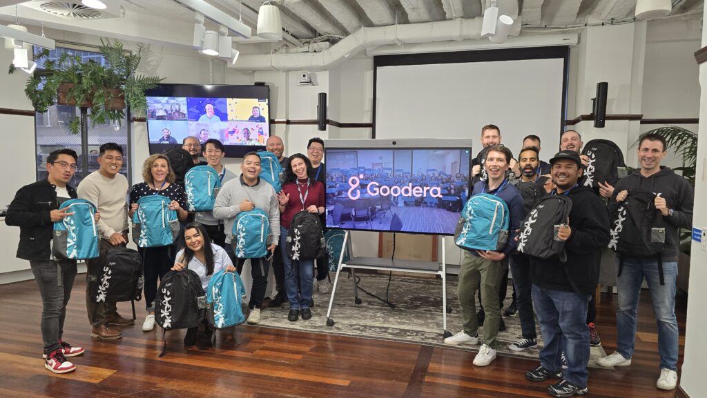Team holding backpacks at Goodera office event