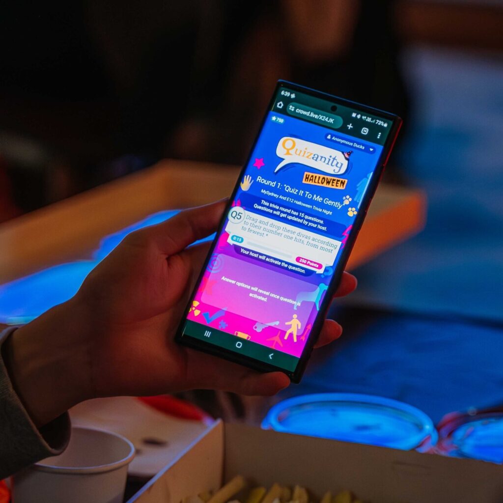 Person holding smartphone showing Halloween trivia quiz app